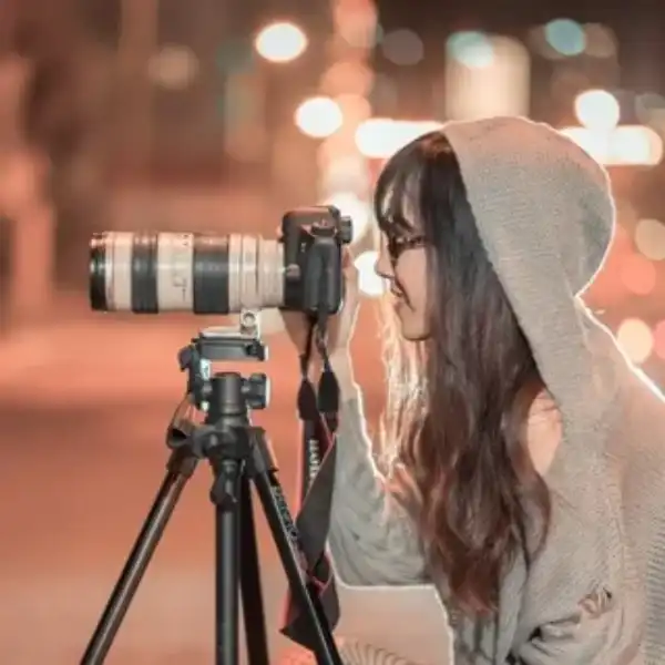 femme à lunettes et veste à capuche de profil prend une photo